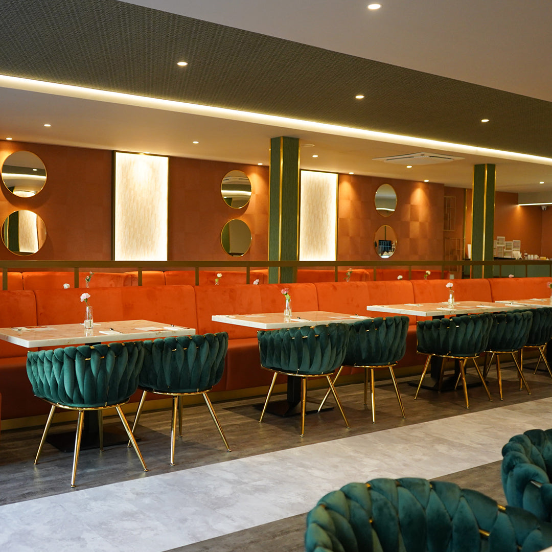 Modern restaurant interior with orange booths, green chairs, and a stylish decor.