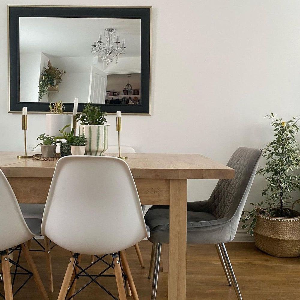 White moulded dining chairs and a grey velvet chair around an oak dining table