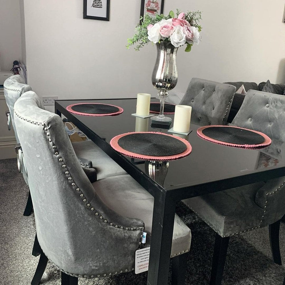 Grey Windsor LUX velvet dining chairs with studded trim around a black glass table