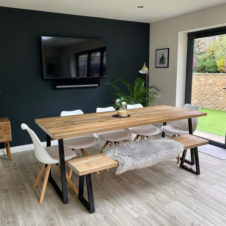 White Jamie Lorenzo dining chairs and a bench around a rustic wooden dining table