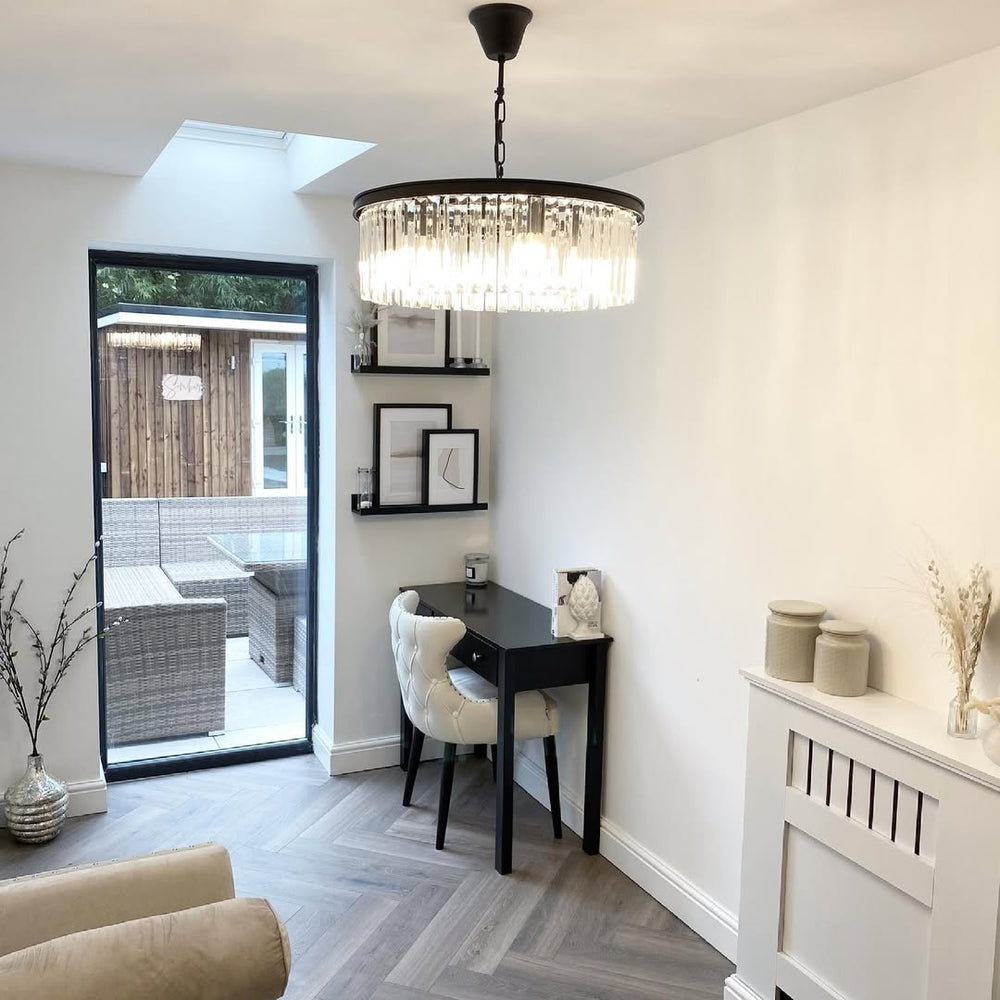 Cream button-back chair at a black desk under a crystal chandelier