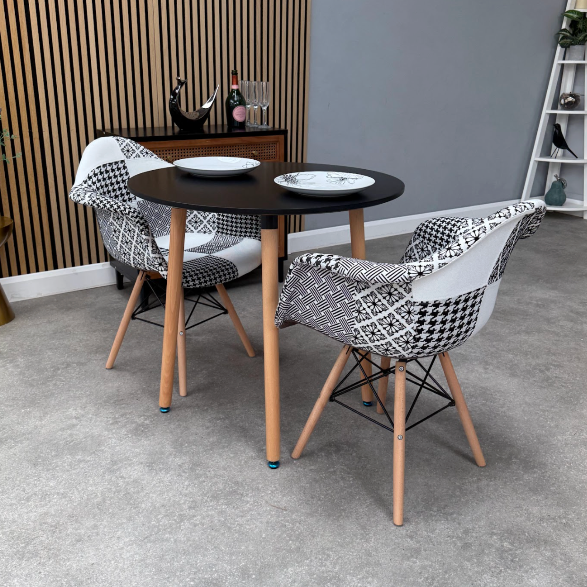 Dining area with a round black table and patterned chairs in a room with gray walls and a wooden floor.