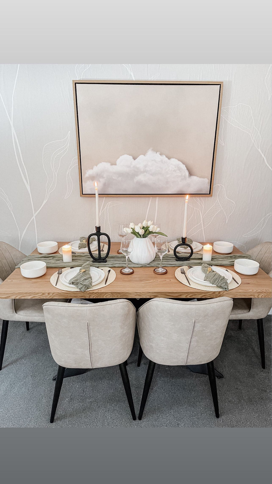 Oak Duke LUX dining table set for dinner with cream chairs and candles beneath a cloud artwork