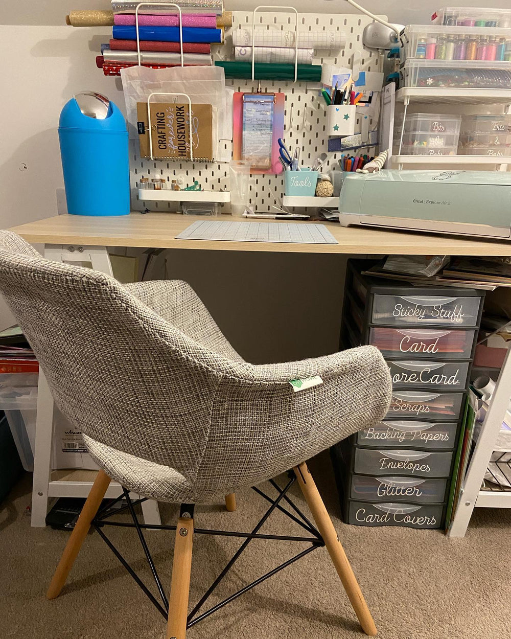 Grey Olivia fabric armchair at a craft room desk with a pegboard of supplies