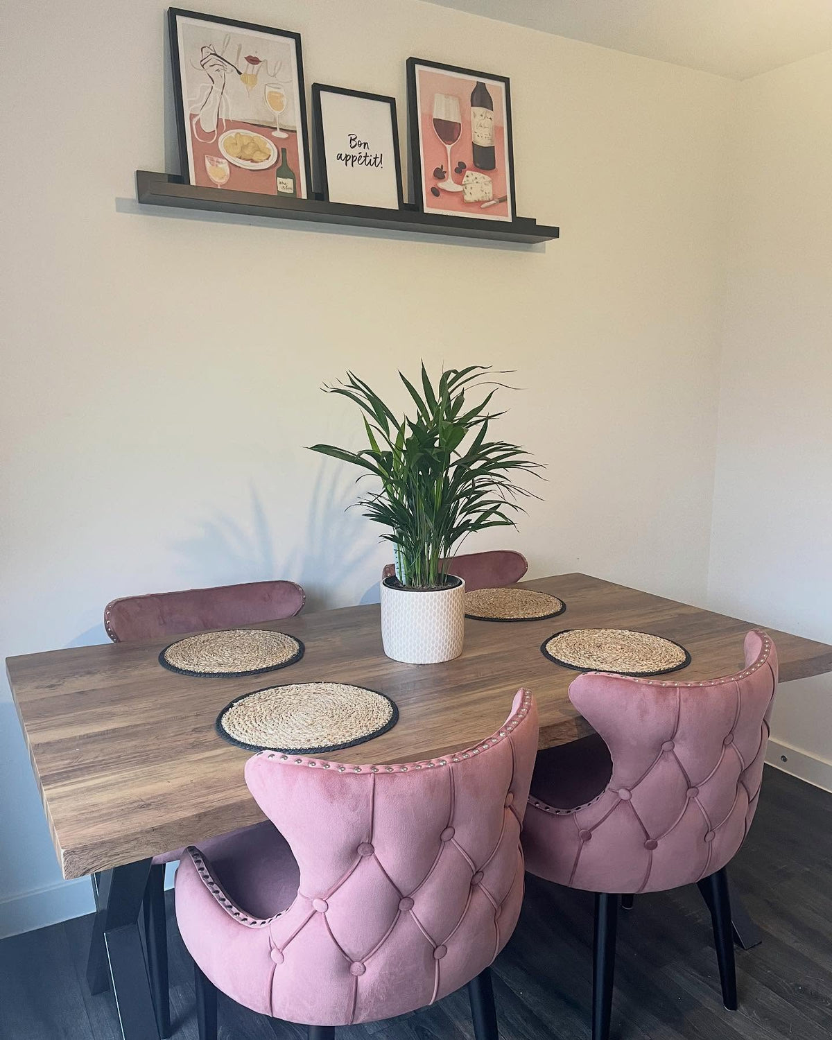 Dusky pink Oxford velvet dining chairs around a wooden dining table with a plant and wall prints