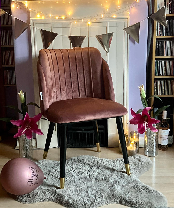 Pink Milano velvet chair with black and gold legs in a living room with fairy lights and bunting